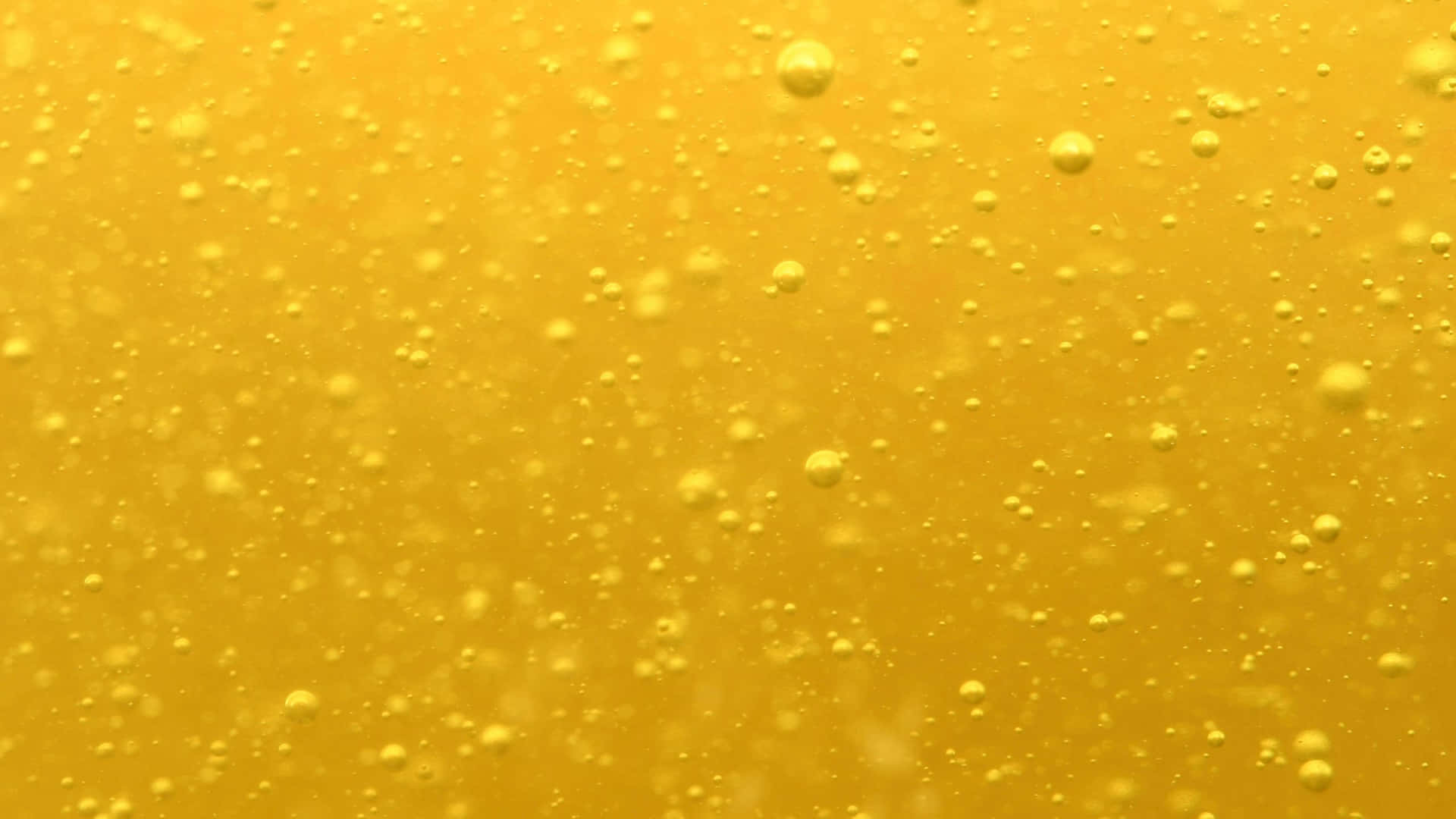 A Close Up Of A Yellow Beer Glass With Water Droplets