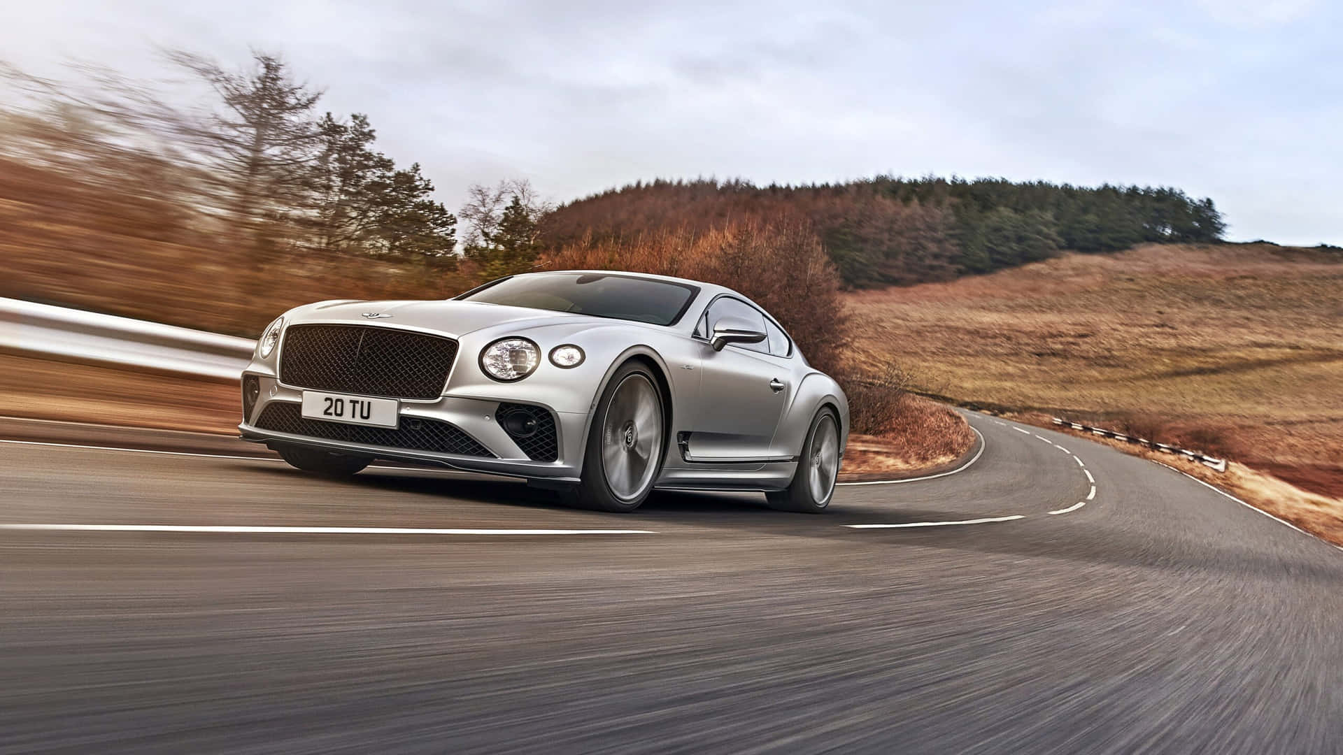 The Bentley Continental Gt Is Driving Down A Road Wallpaper