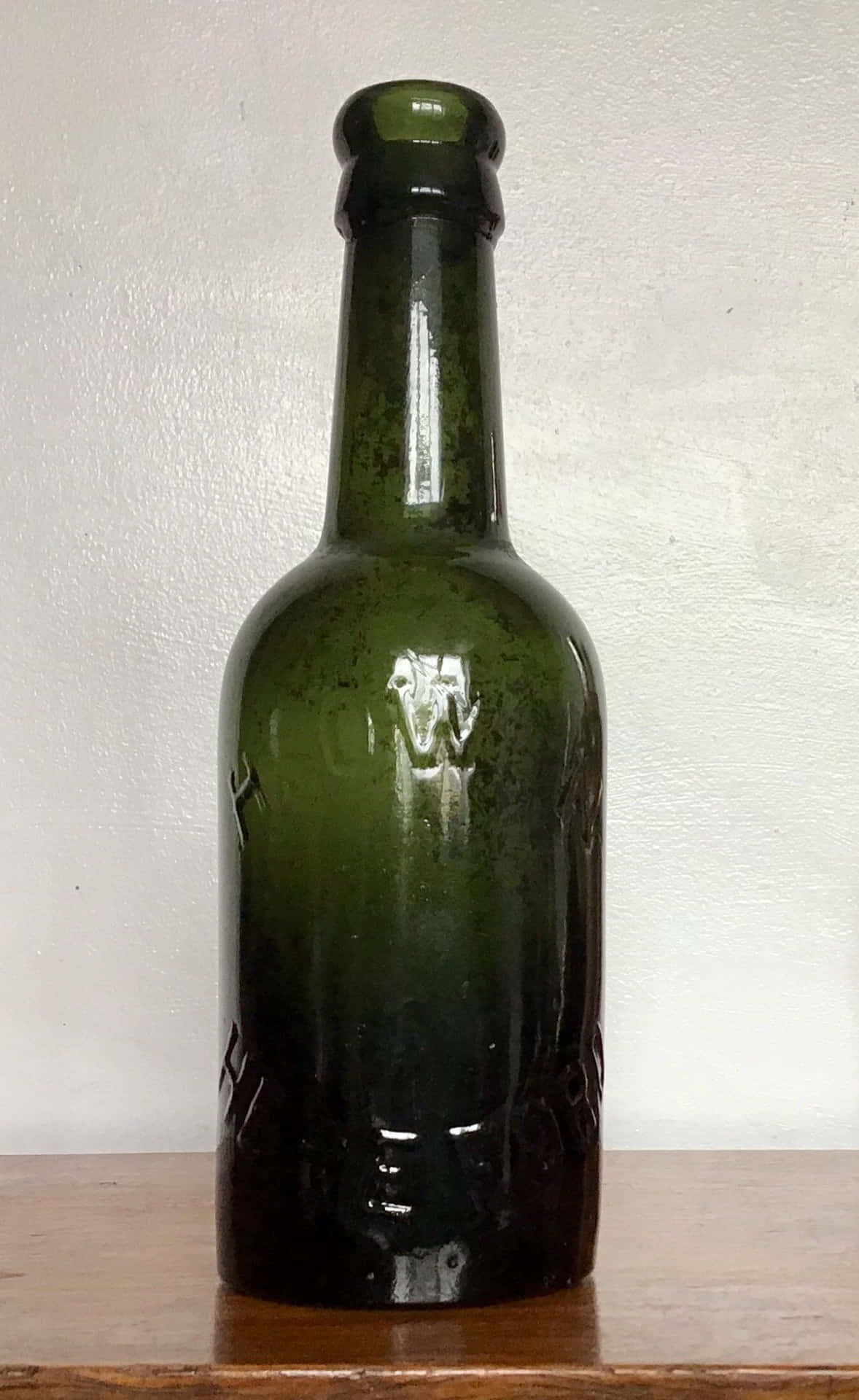 A Green Bottle Sitting On A Wooden Table