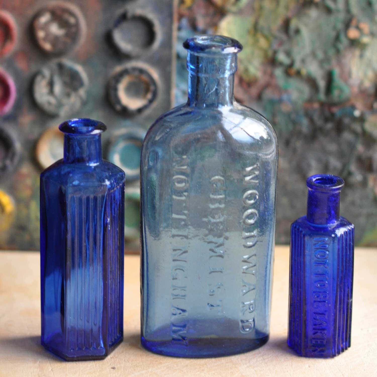 Three Blue Glass Bottles On A Table