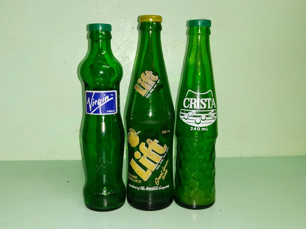 Three Green Bottles With Different Labels On Them