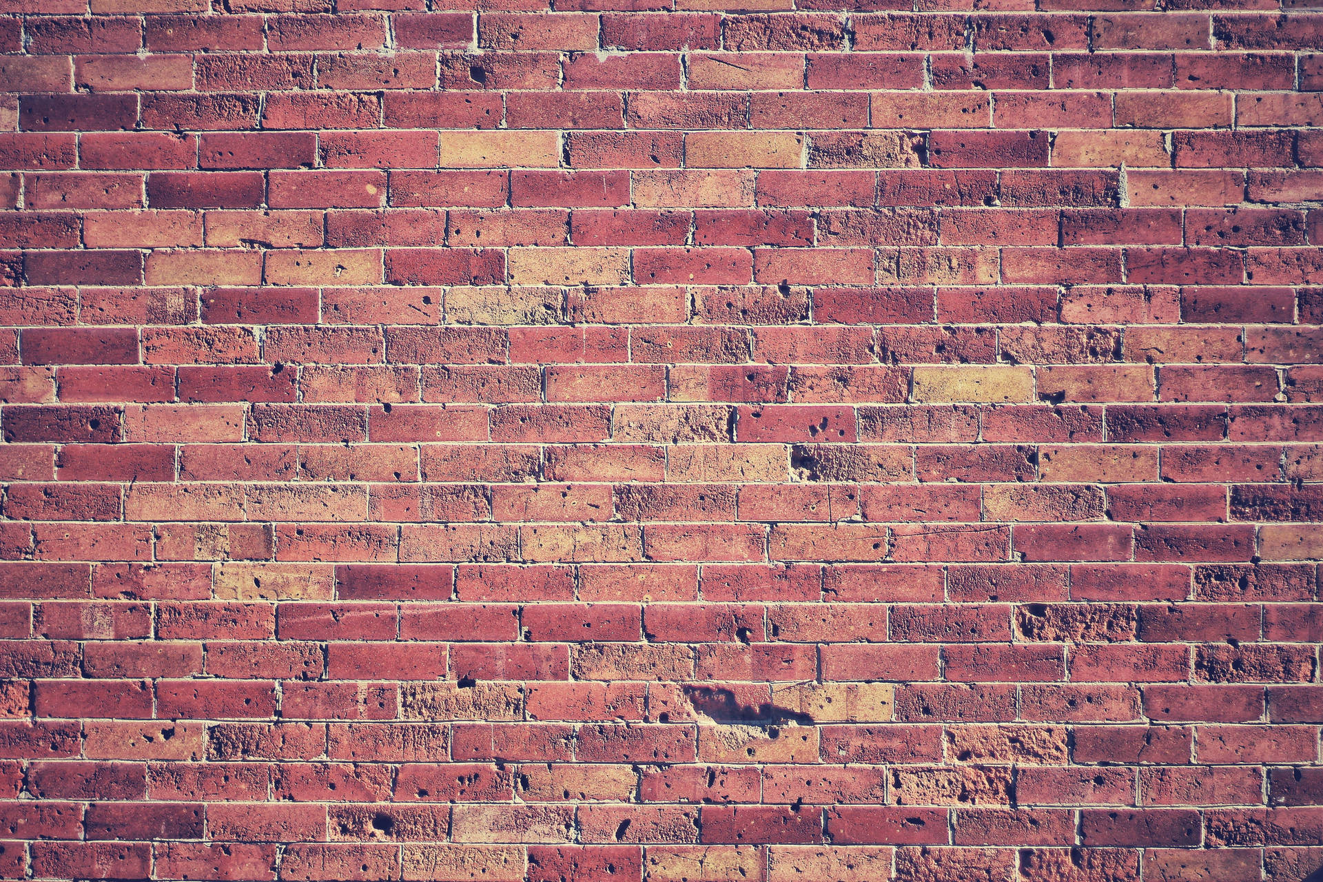 A close-up view of aged, stacked bricks. Wallpaper