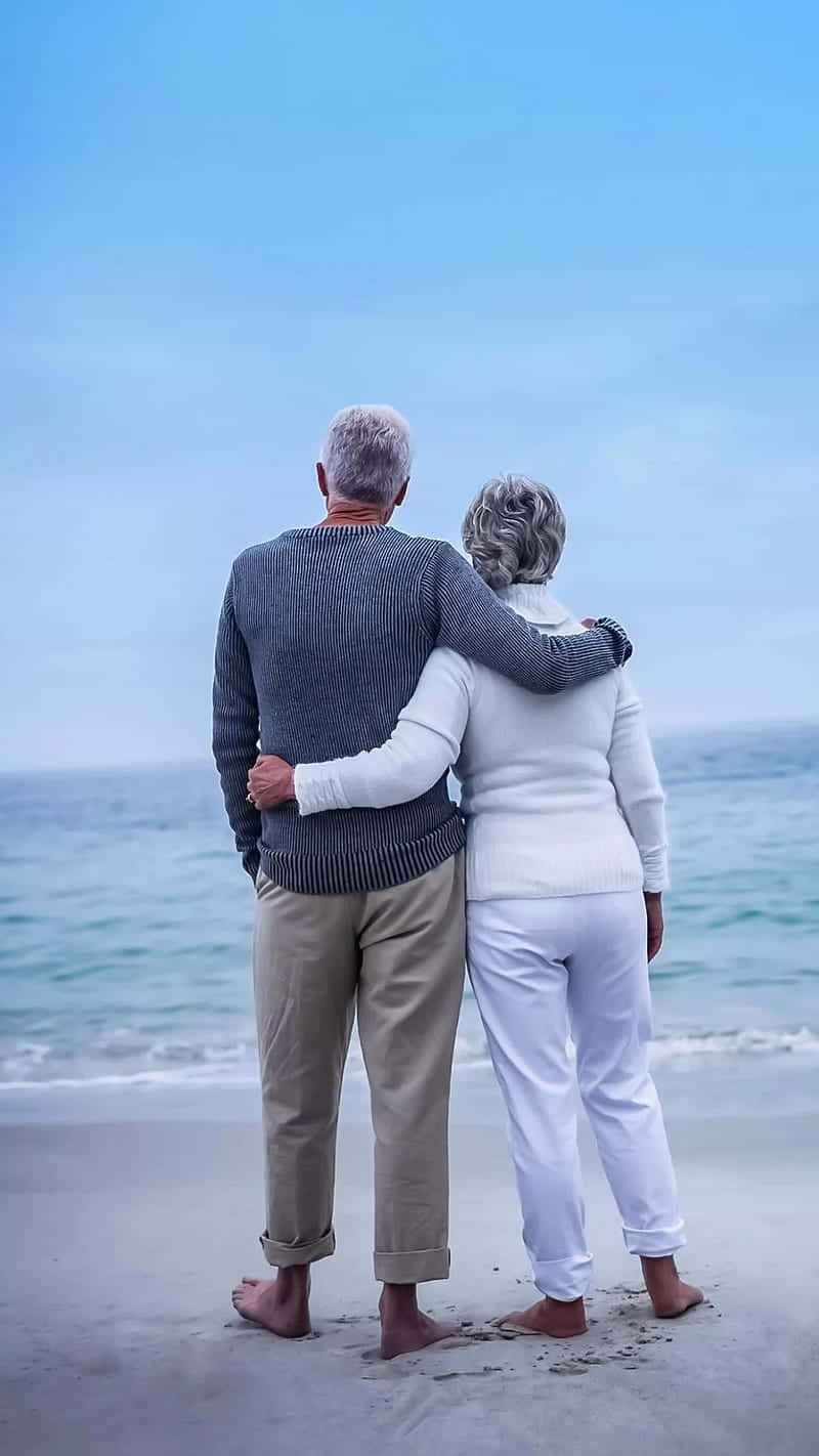 Ældre par, der vender sig mod strandscenen Wallpaper