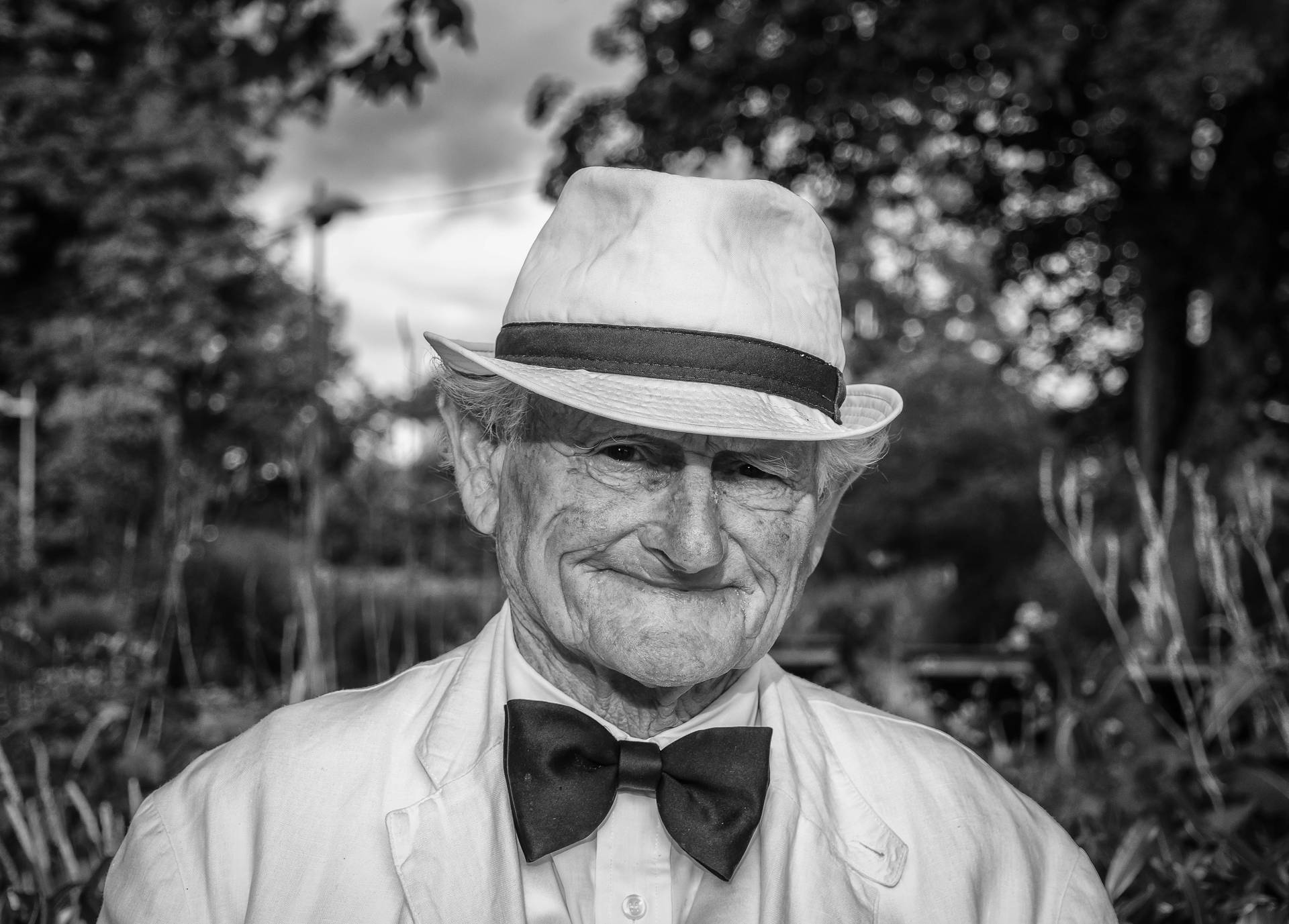 Portrait of a wise old man in a white hat and grey suit Wallpaper