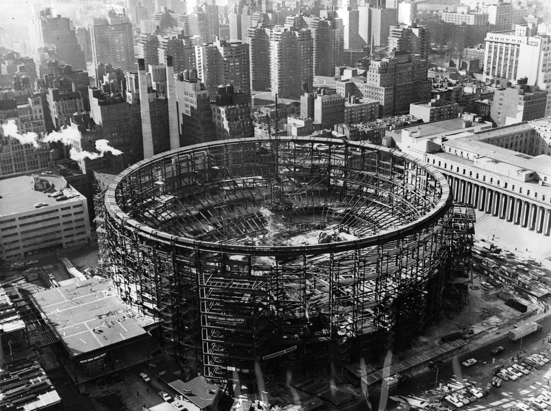 A Large Circular Building Under Construction In A City Wallpaper