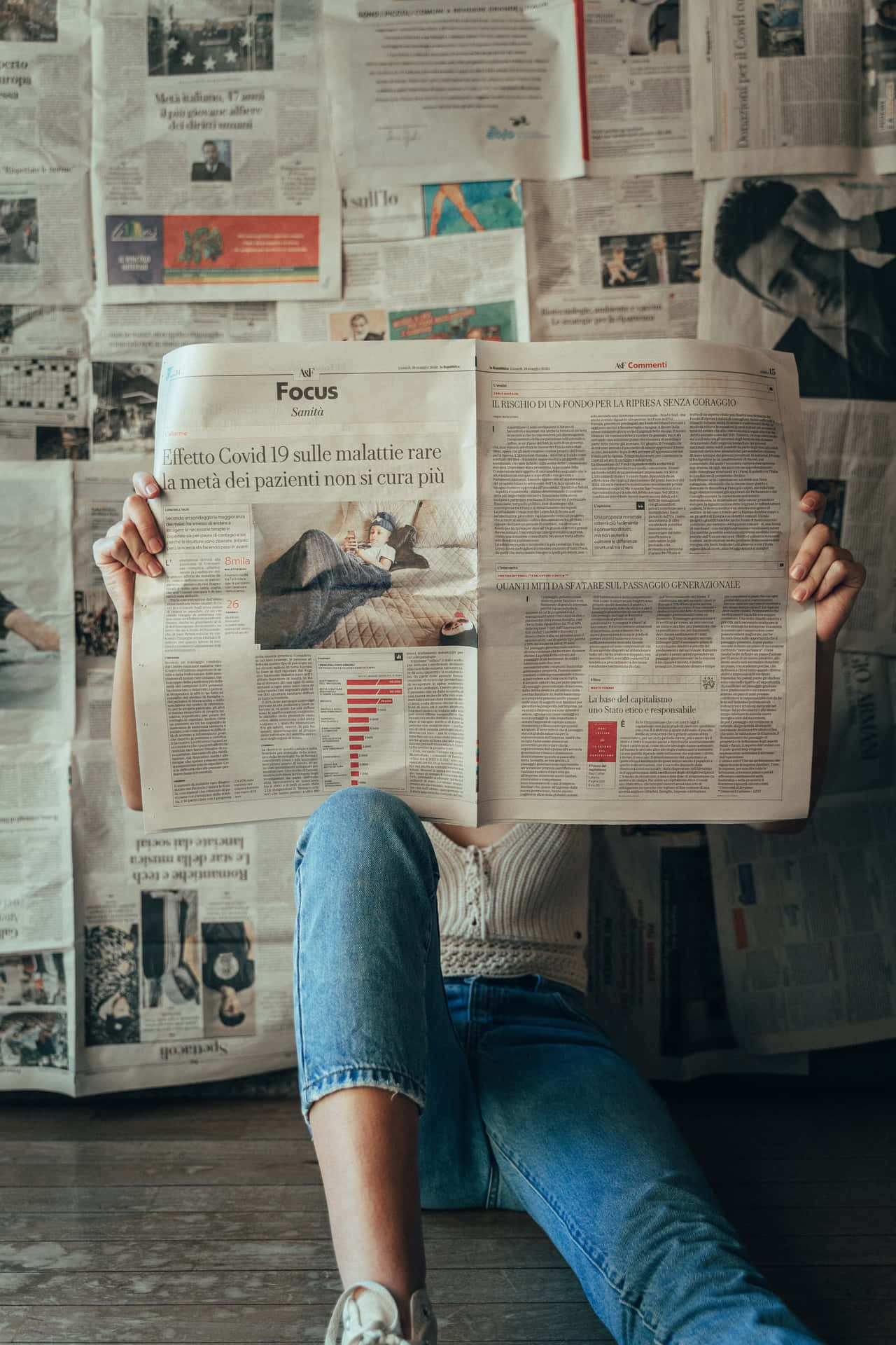 A Woman Sitting On The Floor Reading A Newspaper