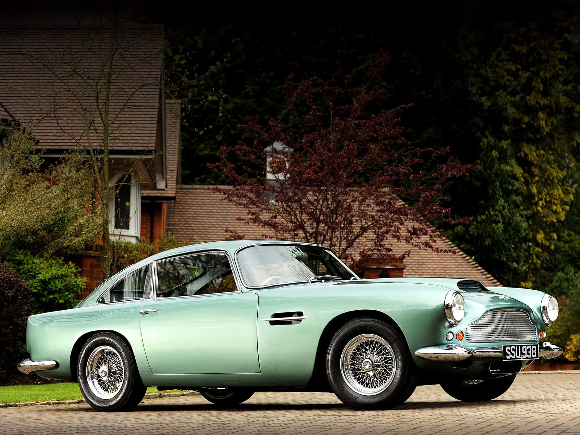 A Green Aston Martin Db5 Parked In Front Of A House Wallpaper