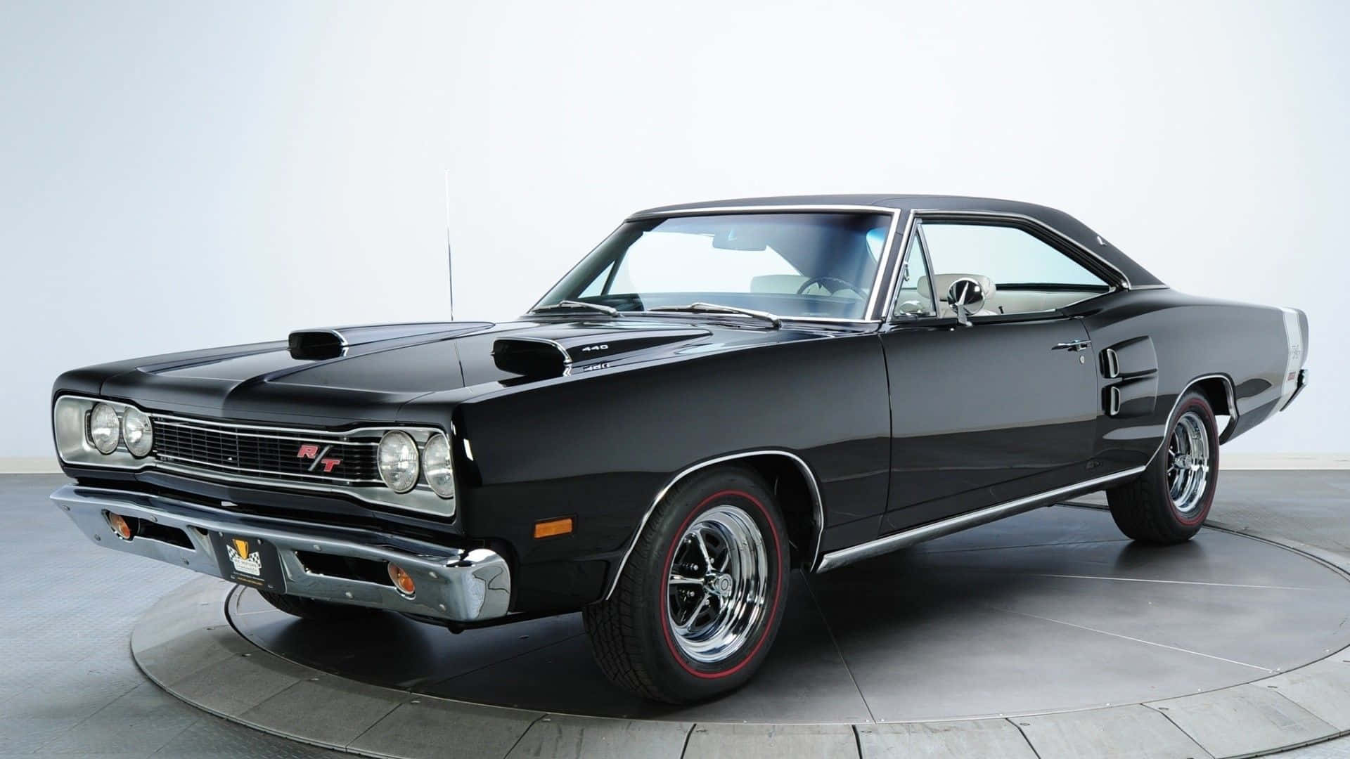 A Black Muscle Car Is Parked On A Circular Platform Wallpaper