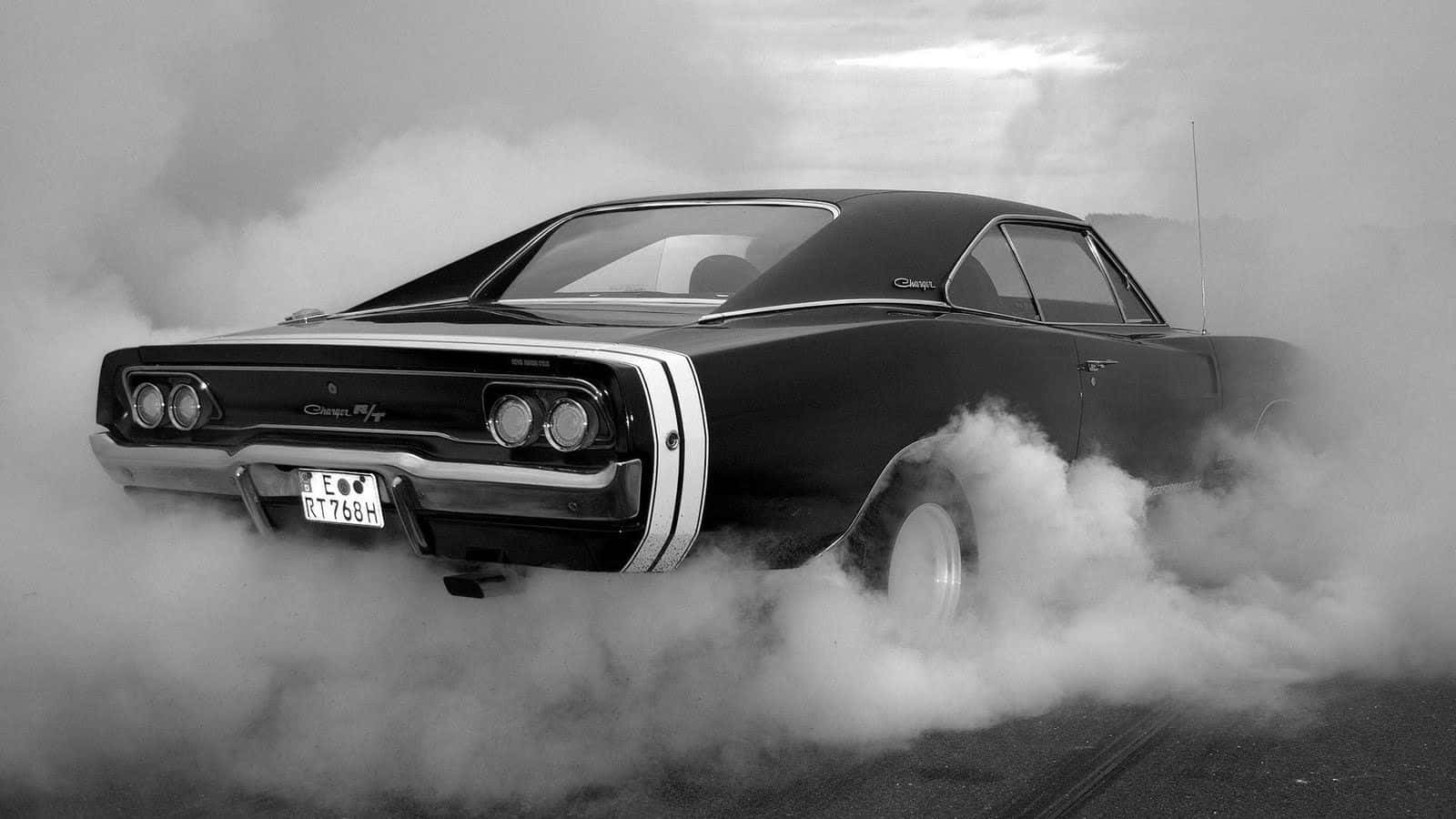 Et sort-hvidt fotografi af en bil med røg, der kommer ud af den. Wallpaper