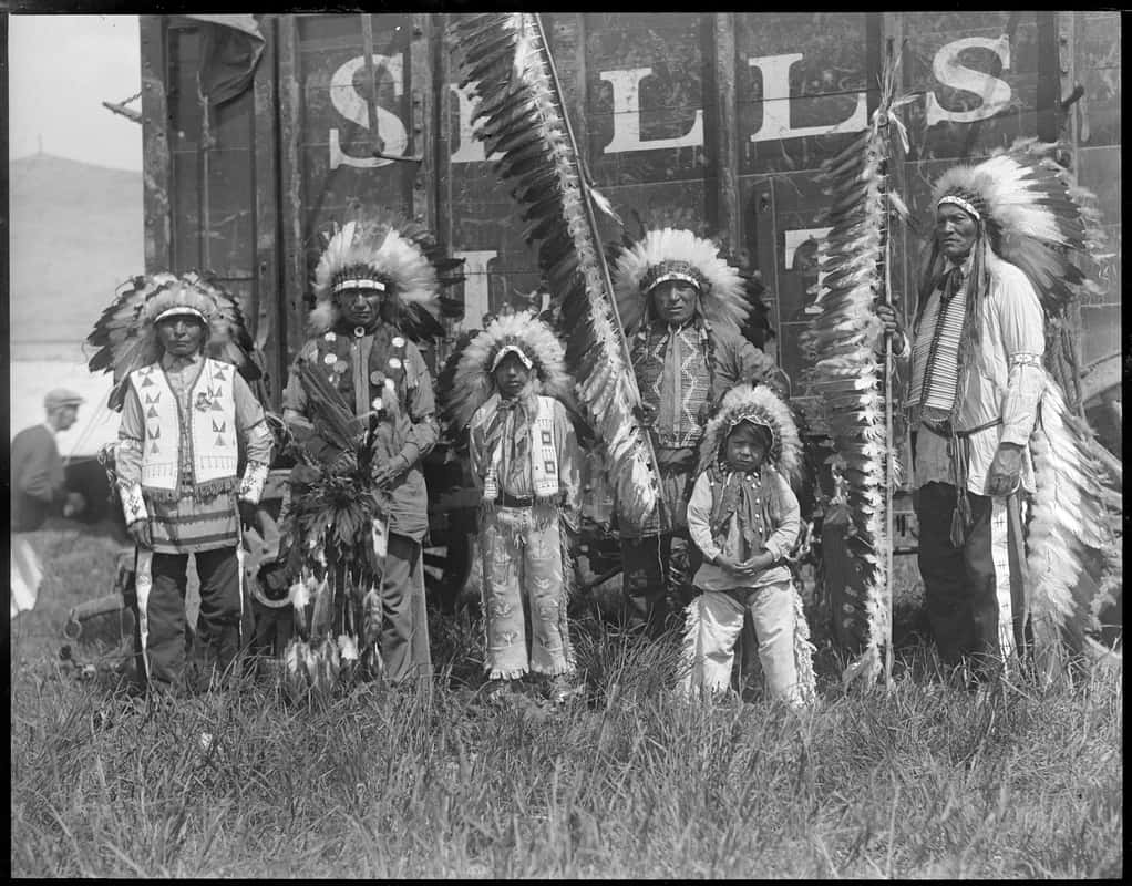 A Group Of Native Americans Standing In Front Of A Train