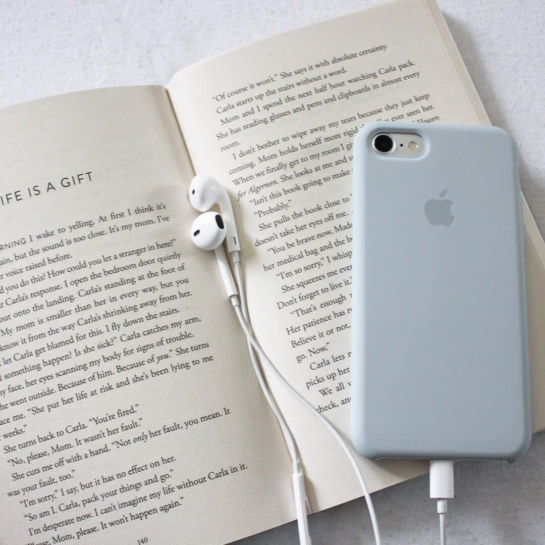 A Book With Earphones And A Phone On Top