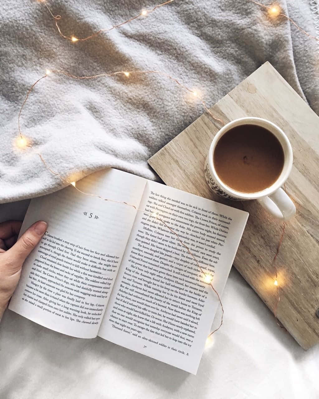 A Person Is Reading A Book On A Bed With Lights
