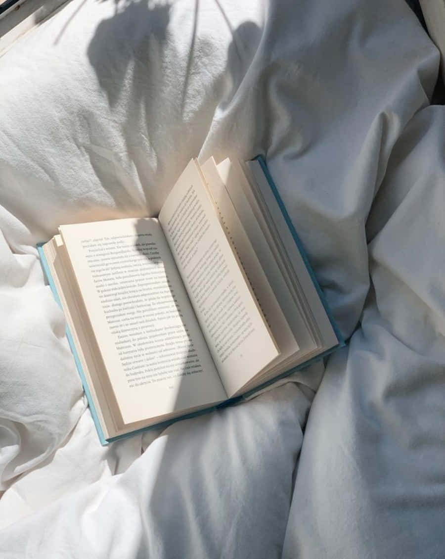 A Book Is Sitting On A Bed With White Sheets