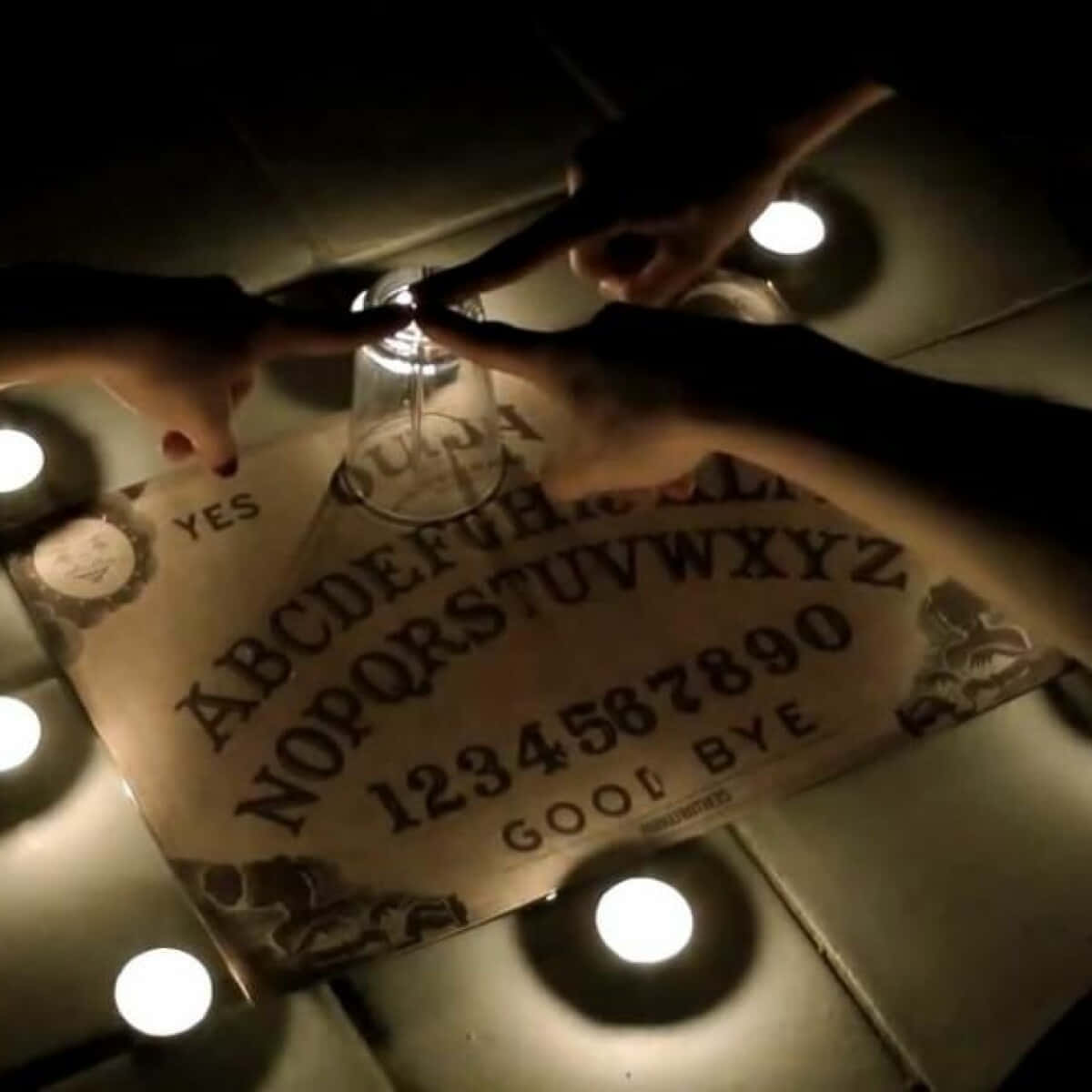 A Person Is Holding A Ouija Board With Candles