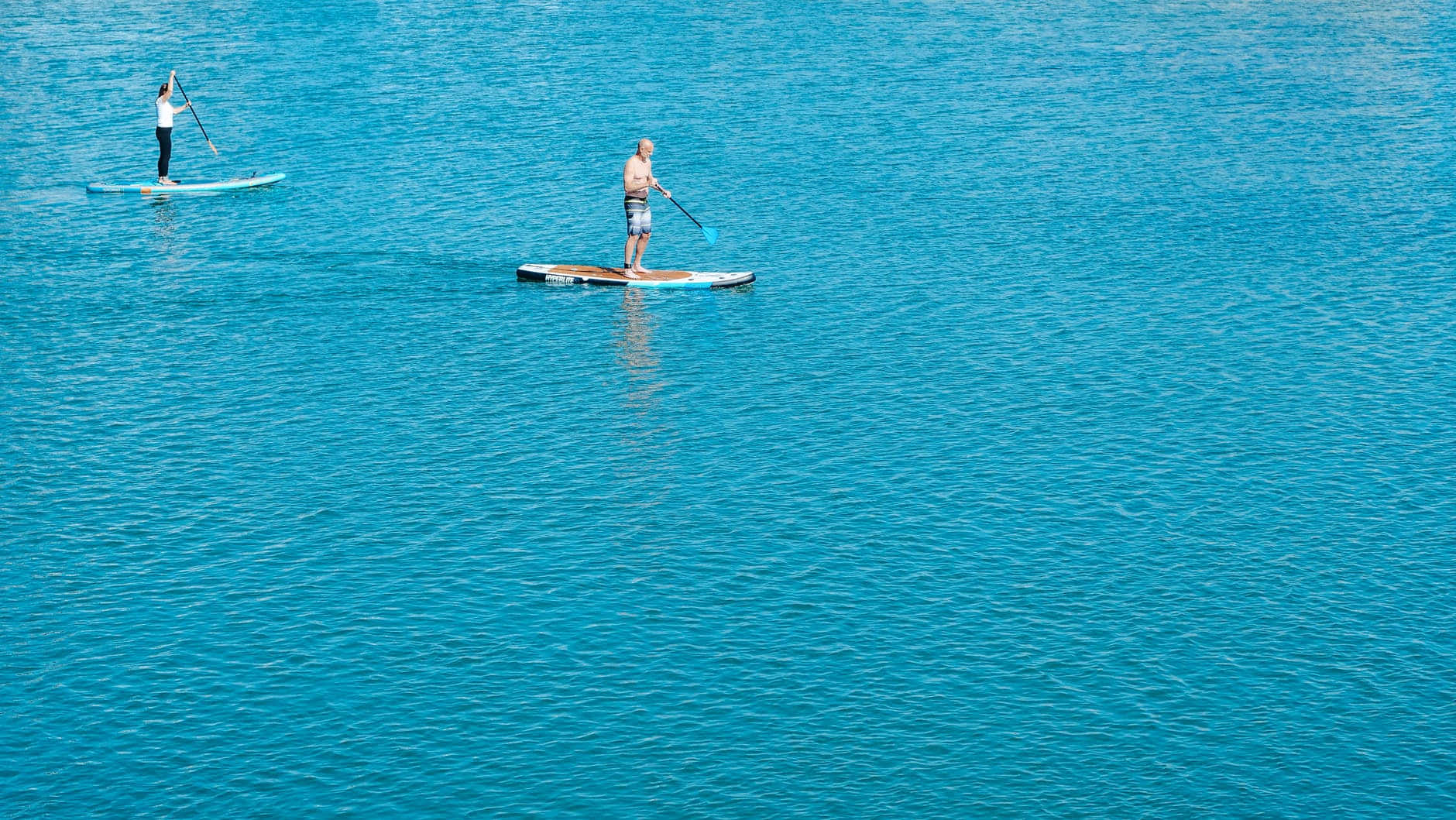 A serene paddleboarding adventure on a calm lake Wallpaper