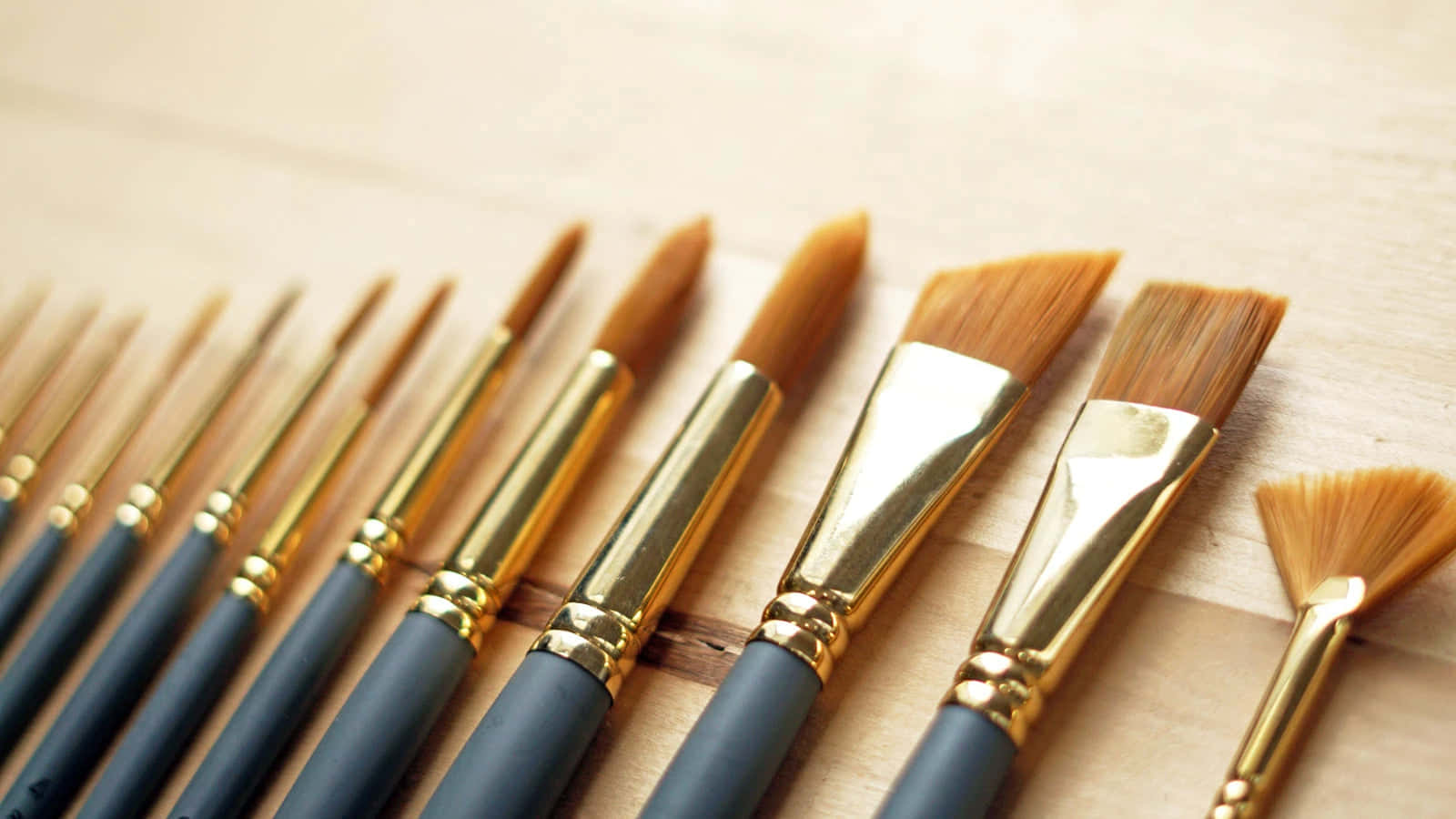 A Group Of Brushes With Gold Handles On A Wooden Surface