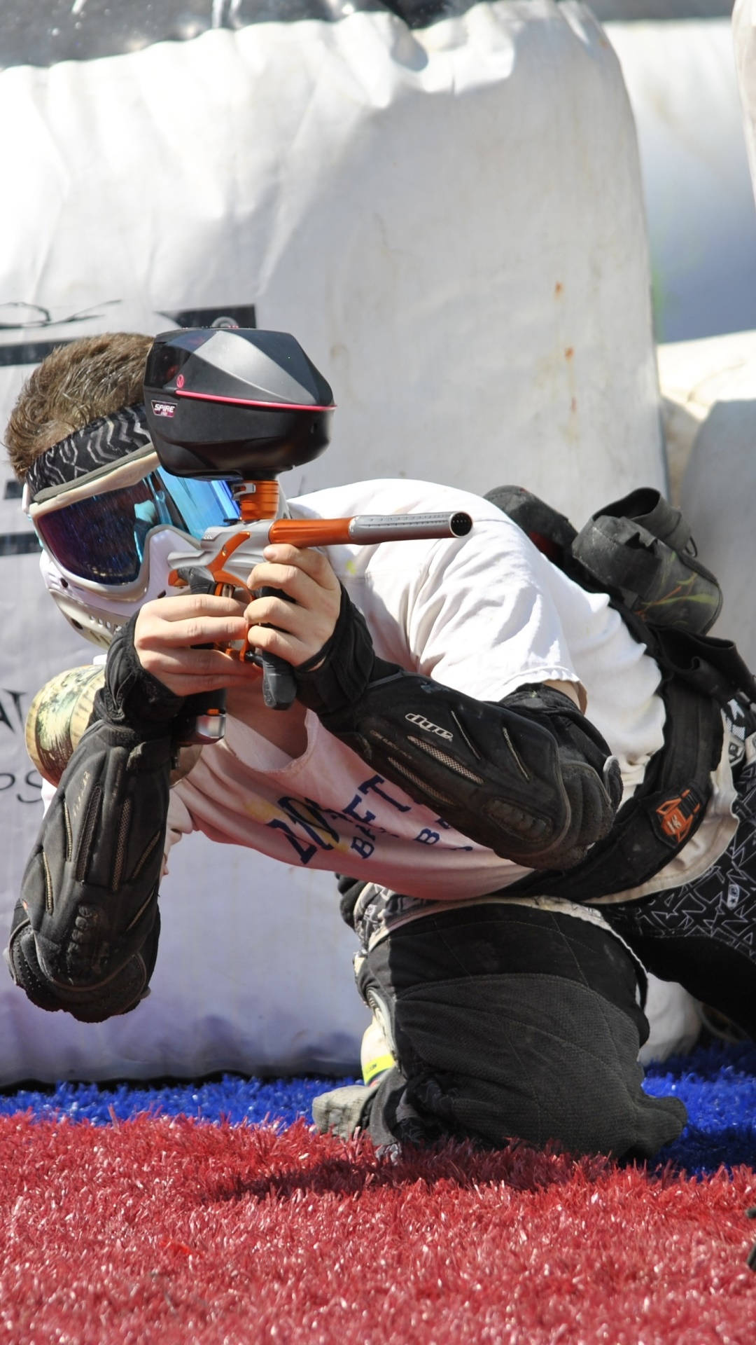 Paintball Player Leaning On Red And Blue Turf Wallpaper