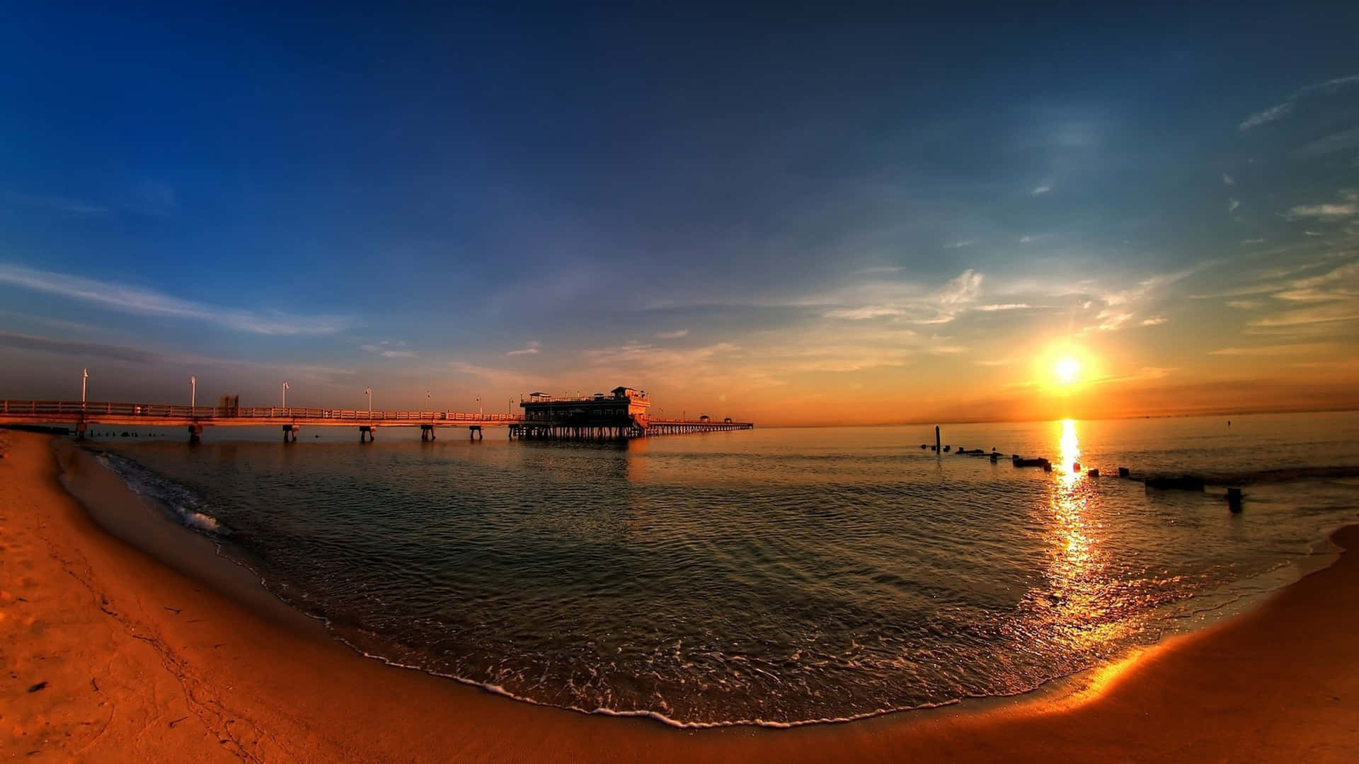 A Panoramic Desktop Background With A Beach And A Pier Wallpaper