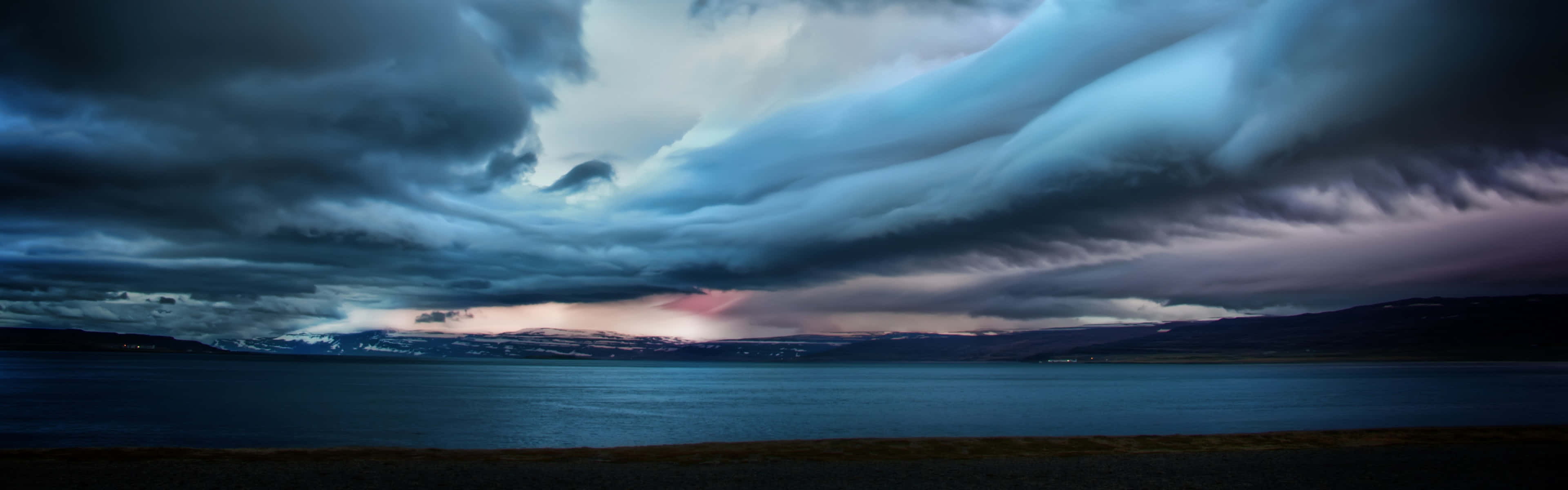 En stormfuld himmel over et sø og bjerge Wallpaper