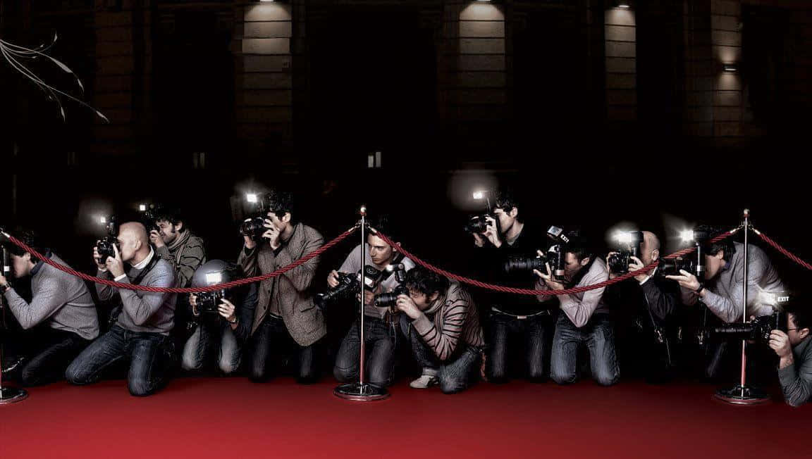 A Group Of People Are Taking Pictures On A Red Carpet Wallpaper