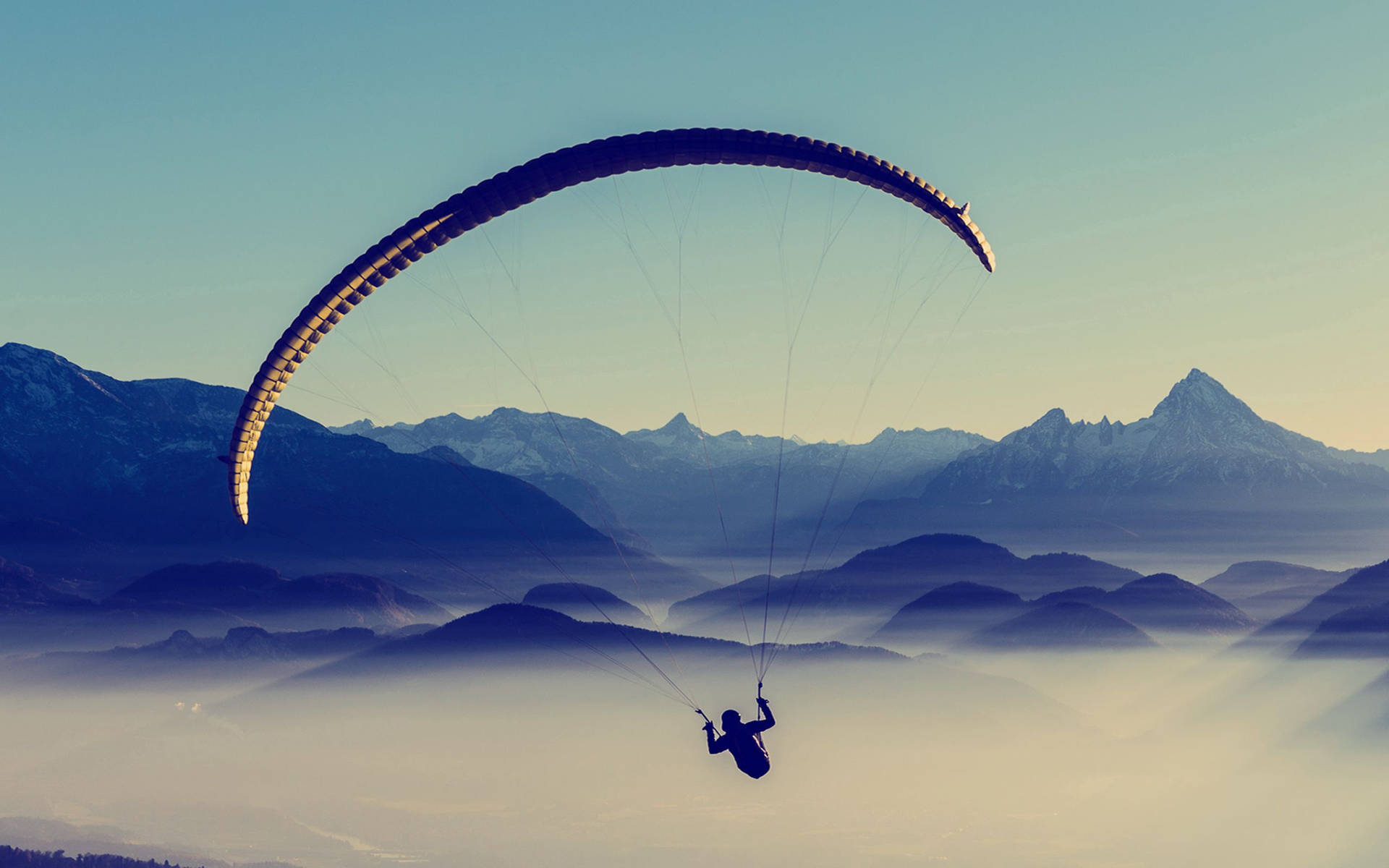 Paraglidingüber Wolkenbedeckten Bergen Wallpaper