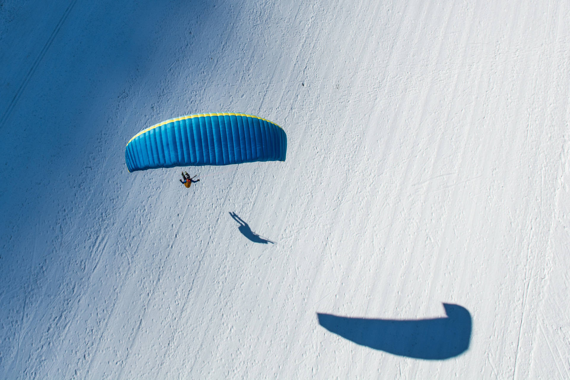 Paraglidingovanför Snö (as A Suggestion For A Computer Or Mobile Wallpaper Of A Paraglider Flying Above Snowy Mountains) Wallpaper