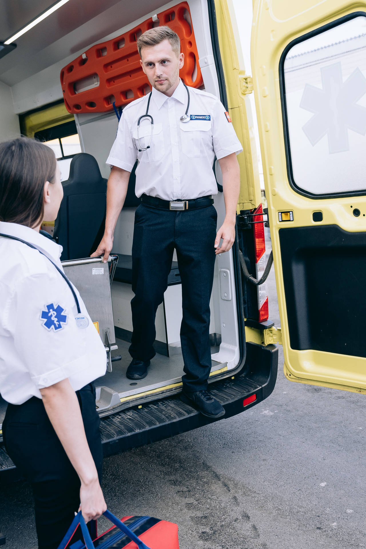 A committed paramedic standing inside an ambulance. Wallpaper