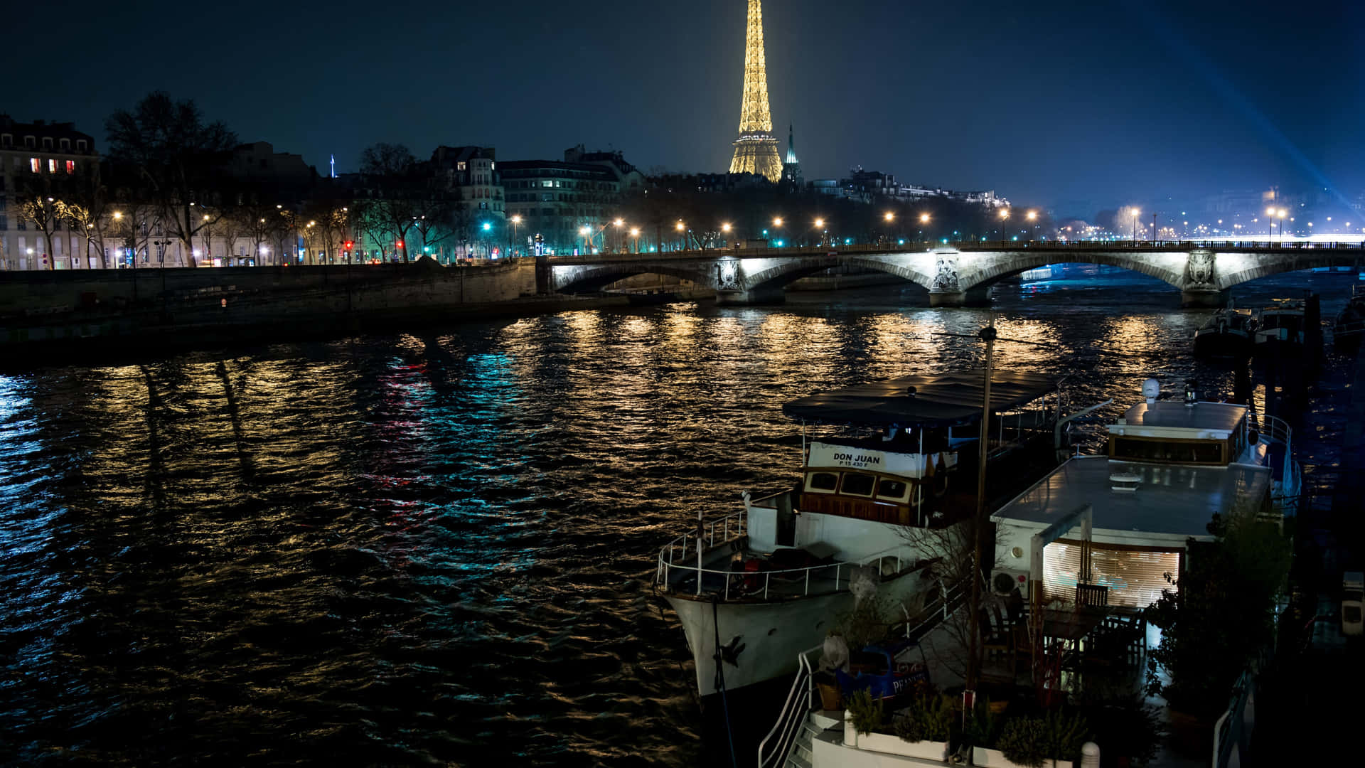 Tag på udsigten til den oplyste Eiffeltårn i Paris om natten. Wallpaper