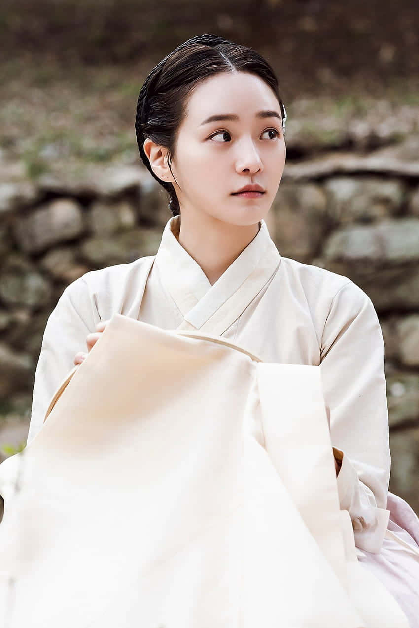 A Woman In A White Kimono Is Sitting On A Stone Wallpaper