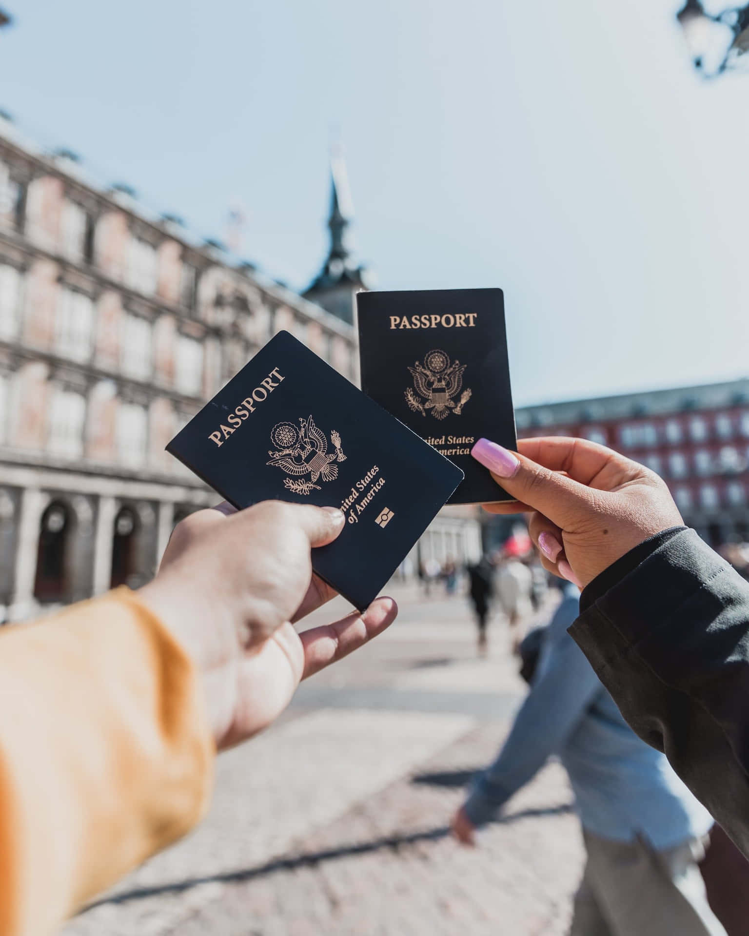 Two People Holding Passports In Front Of A Building