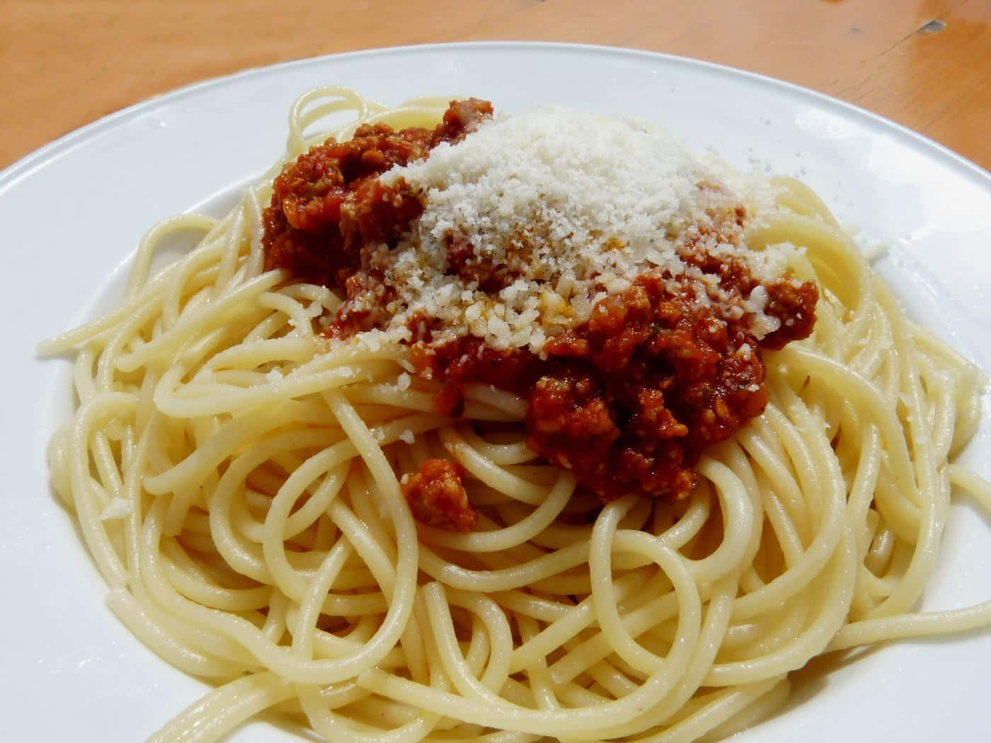 A Plate Of Spaghetti With Meat Sauce And Parmesan Cheese