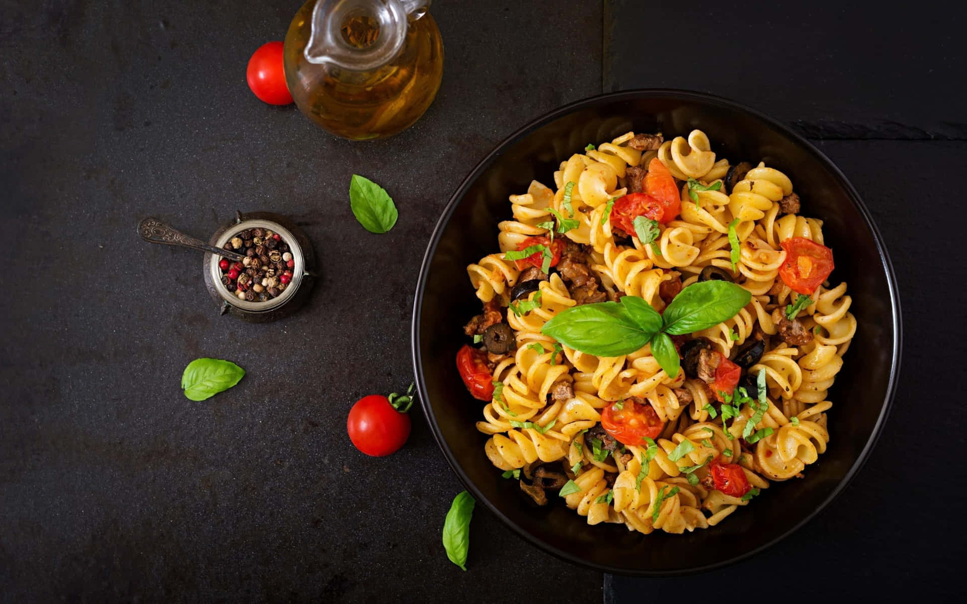 Pasta With Tomatoes And Basil On A Black Plate