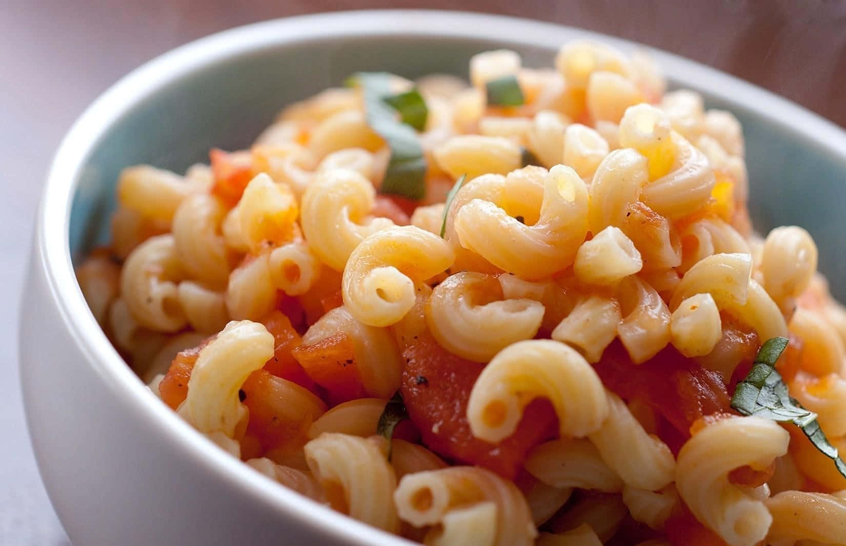 A Bowl Of Pasta With Tomatoes And Basil