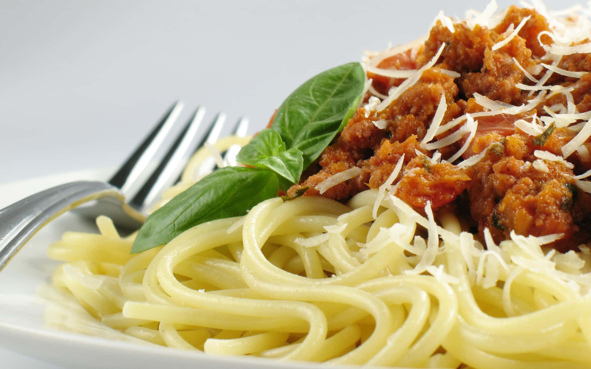 A Plate Of Spaghetti With Meat Sauce And Basil