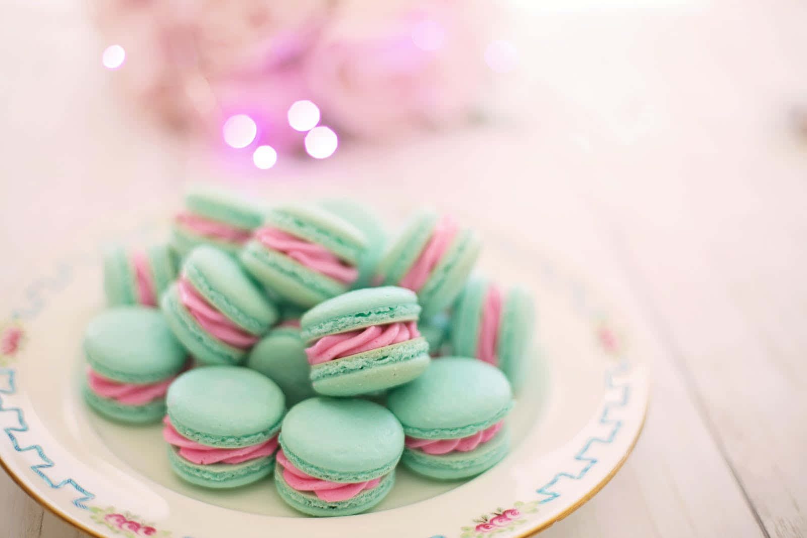 A Plate Of Pink And Green Macarons On A Table Wallpaper