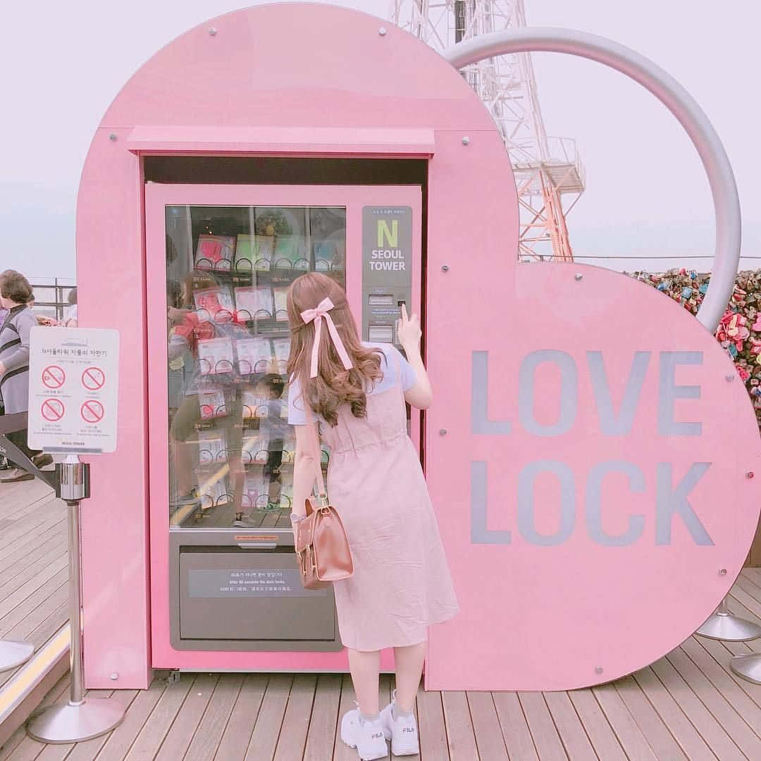 A Woman Standing In Front Of A Pink Vending Machine