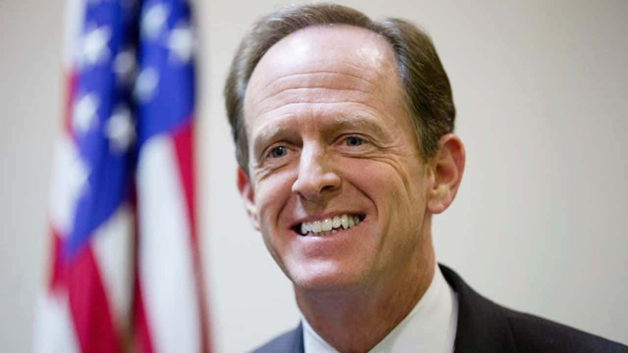 Pat Toomey Smiling With Flag Wallpaper