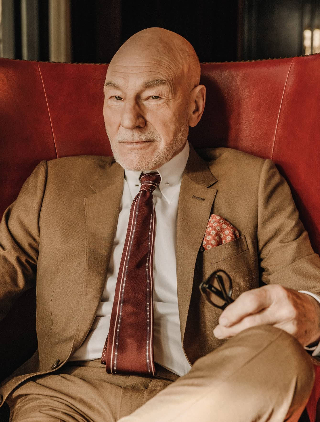 Distinguished Actor Patrick Stewart Relaxing on a Red Couch Wallpaper