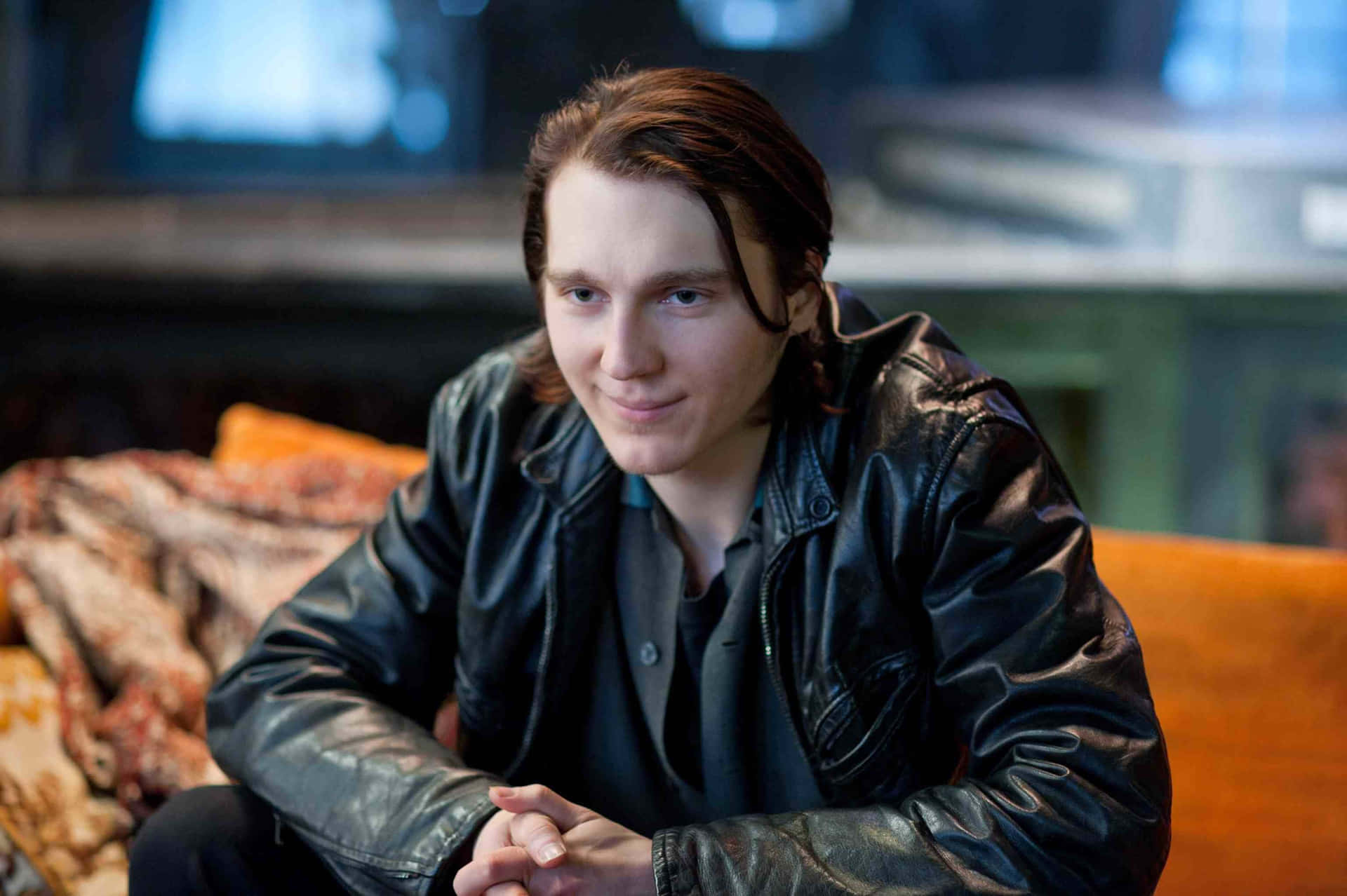 A Young Man Sitting On A Couch In A Leather Jacket Wallpaper