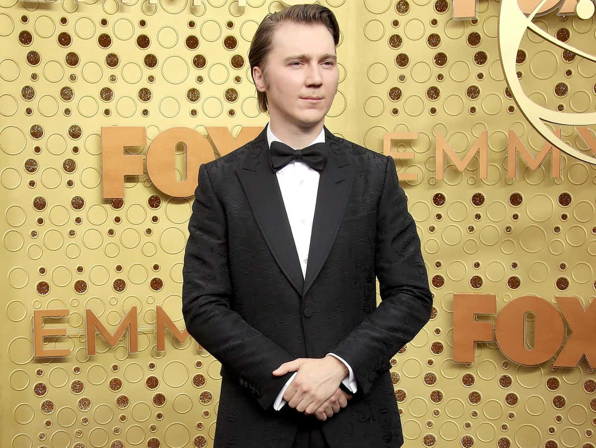 A Man In A Tuxedo Standing On The Red Carpet Wallpaper