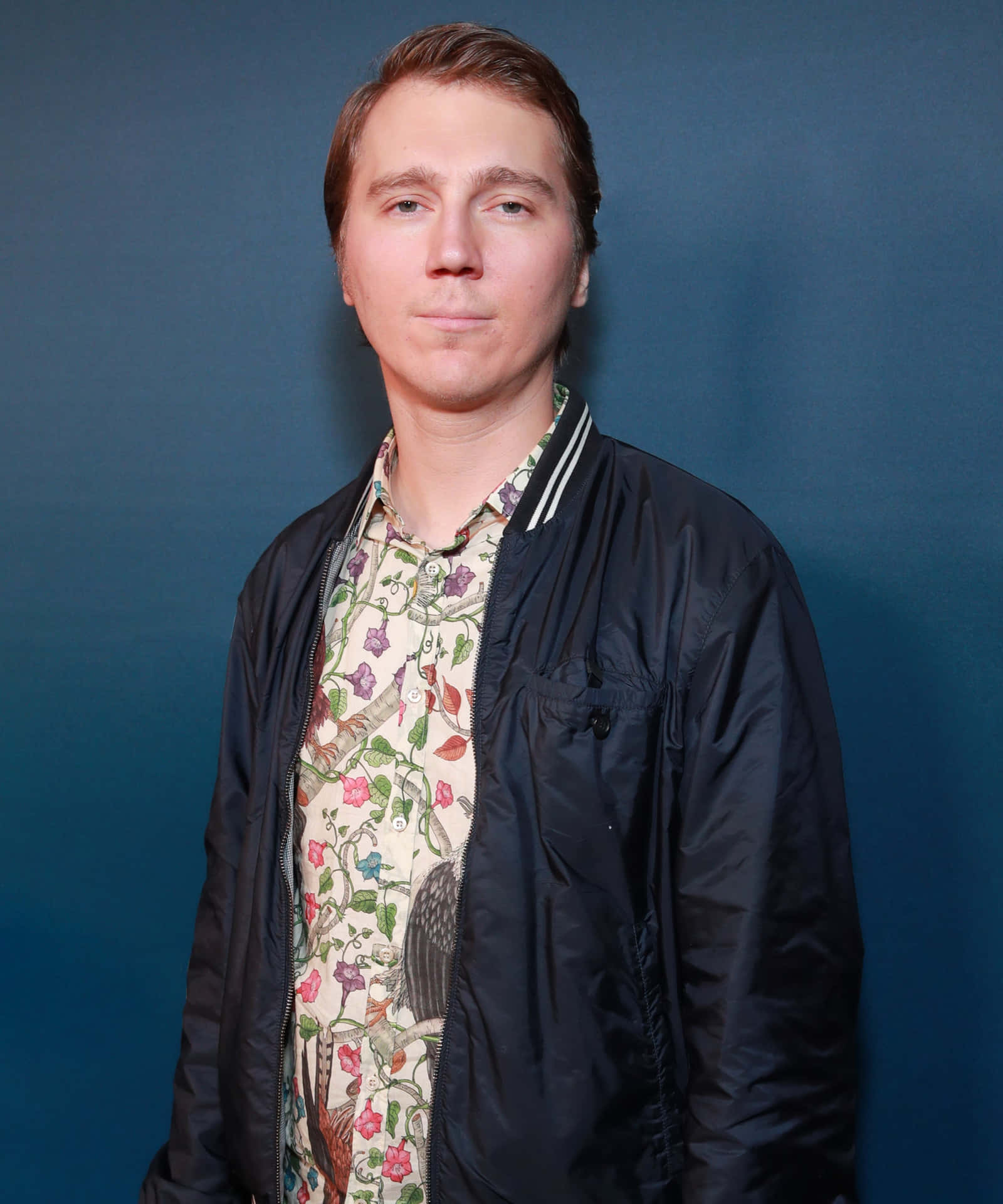 A Man In A Floral Shirt Standing In Front Of A Blue Wall Wallpaper