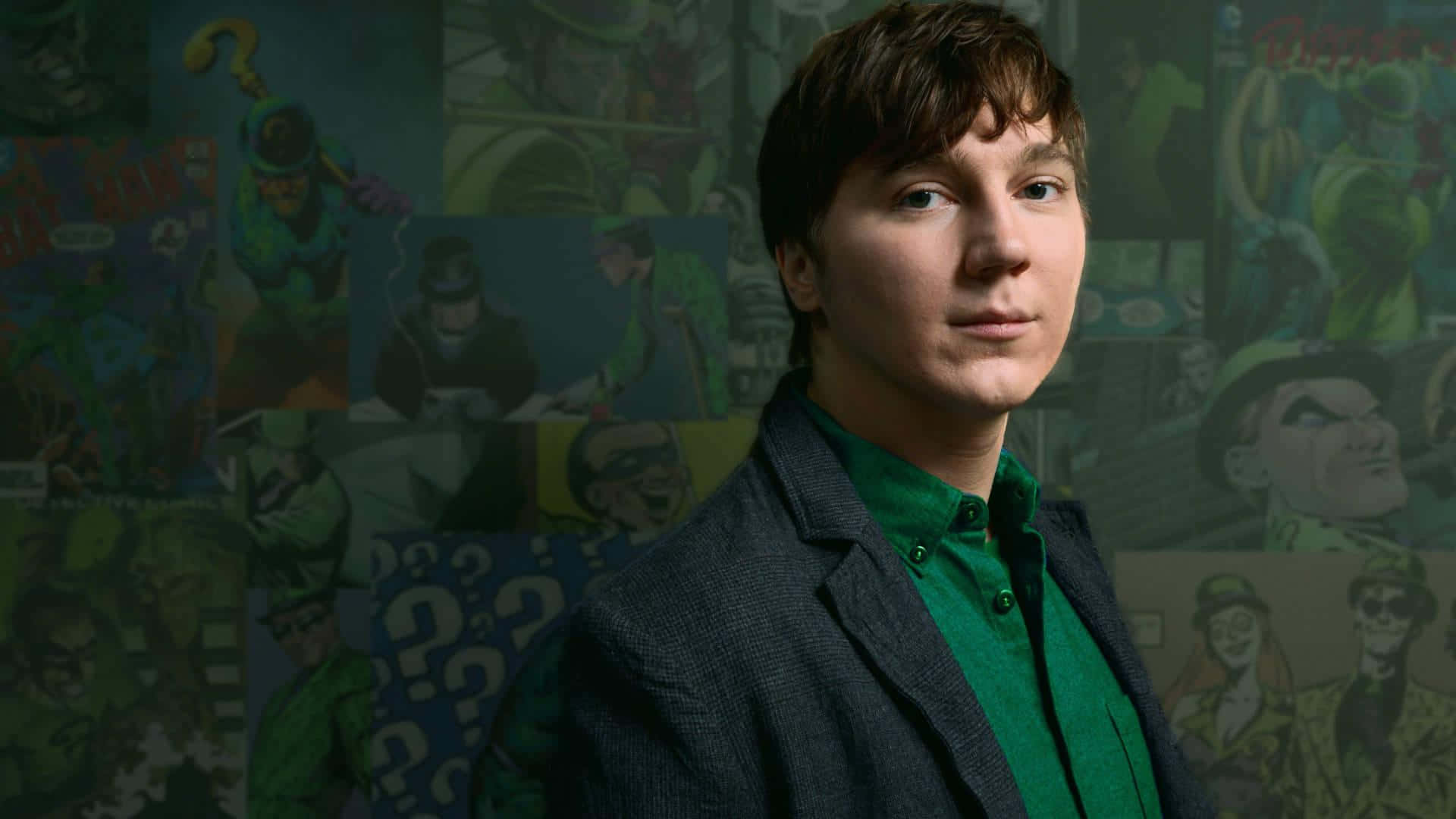 En ung mand i grønt jakkesæt stående foran en væg af tegneserier Wallpaper
