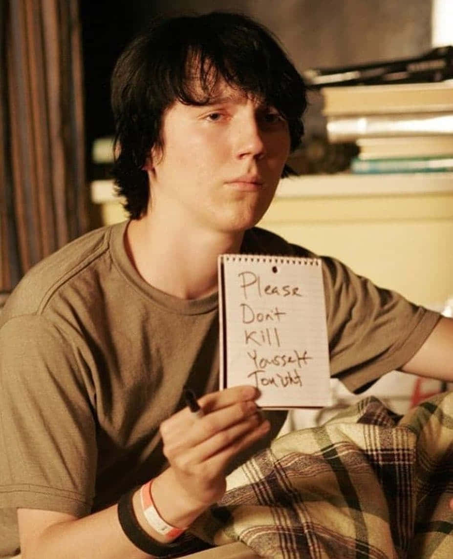 A Young Man Holding A Note In Bed Wallpaper