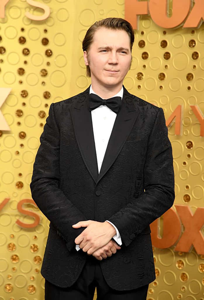 A Man In A Tuxedo Standing On The Red Carpet Wallpaper