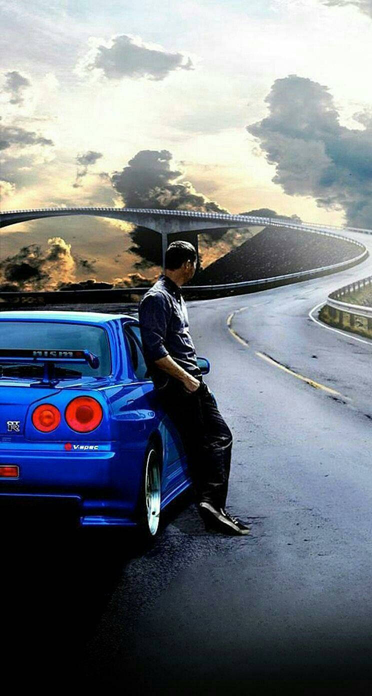 En mand sidder på en blå bil på vejen Wallpaper