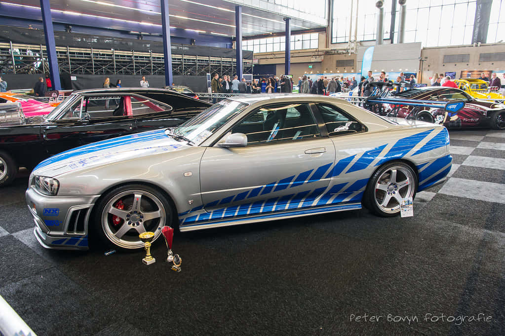 A Blue And Silver Car Is On Display At A Show Wallpaper