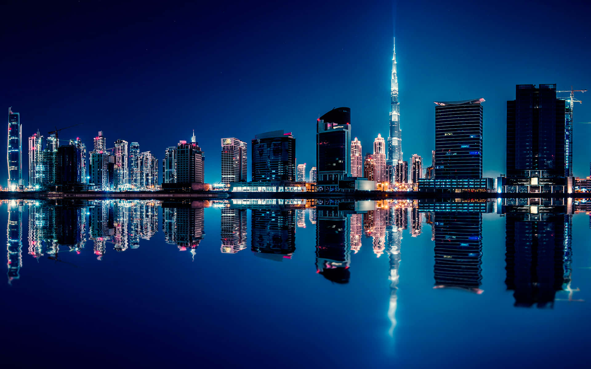 Dubai Skyline At Night With Reflection In Water