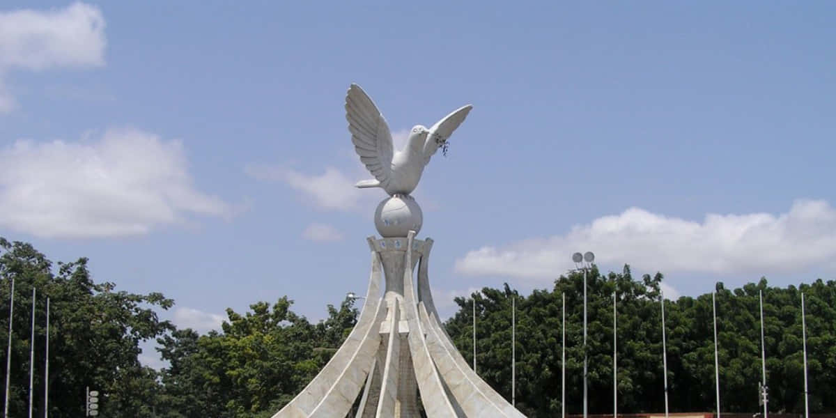 A White Statue Of A Dove With Wings On Top