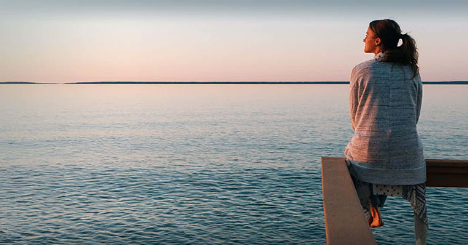 Imagende Una Mujer Sentada En Un Balcón Tranquilo Frente A La Playa