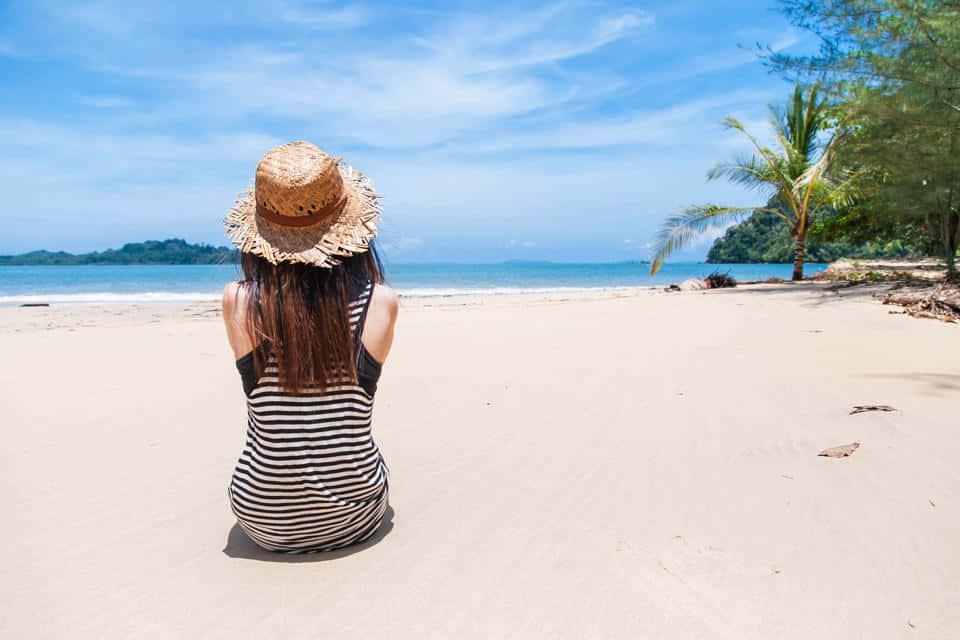 Imagemde Uma Garota Sentada Em Uma Praia Branca E Pacífica.